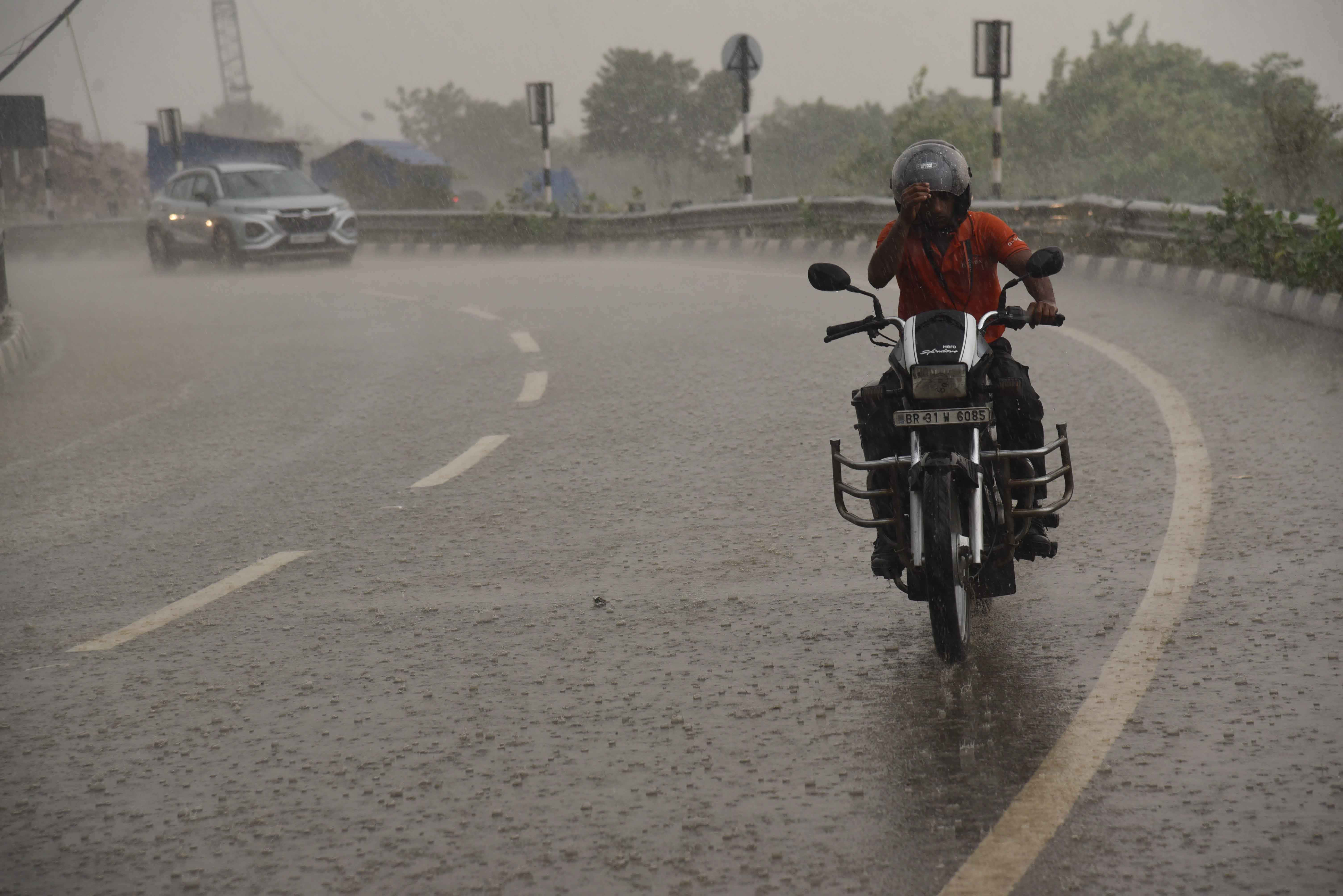 पटना में बारिश के  दौरान सड़क से गुजरते  लोग