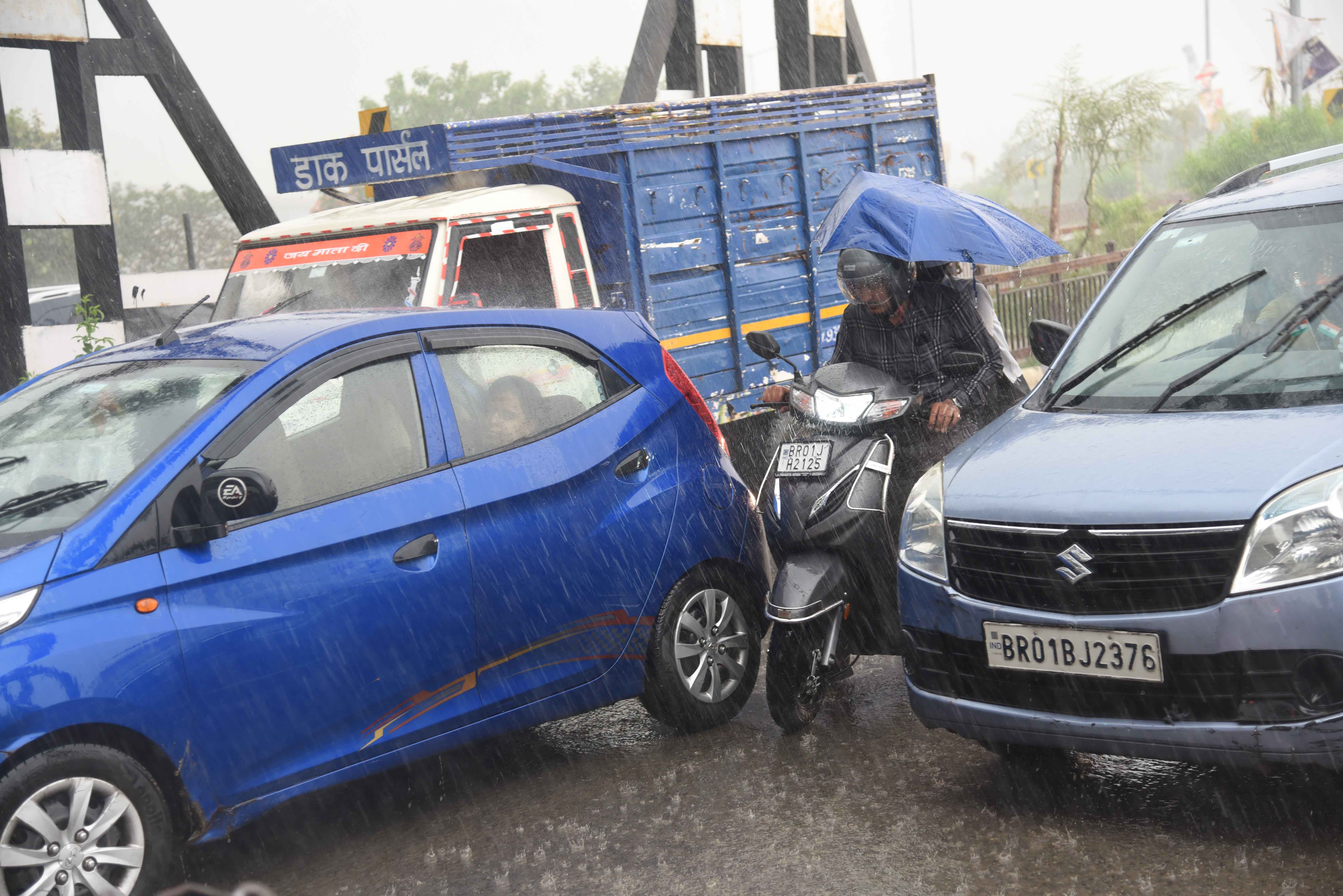 पटना में बारिश के  दौरान सड़क से गुजरते  लोग