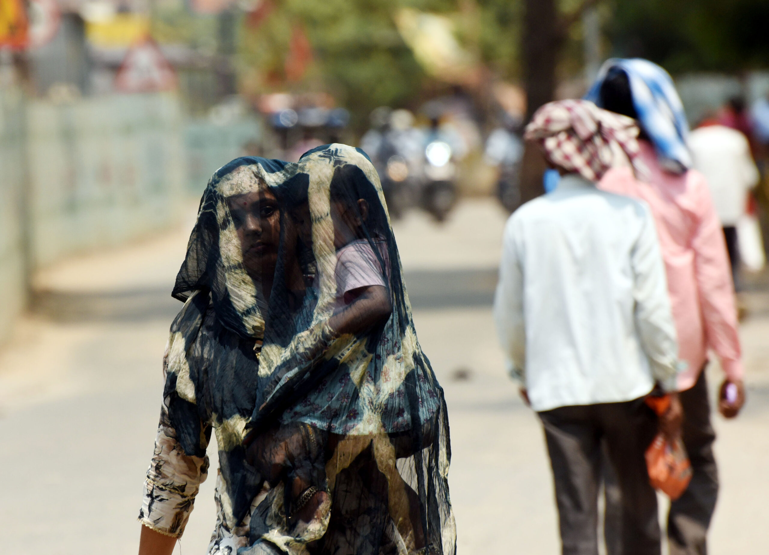 पटना में चिलचिलाती धूप से दुपट्टे के सहारे बचते मां और बच्चा